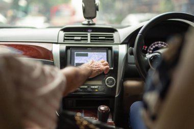 Baba eli, kız araba sürerken dokunmatik ekranda araba sistemi kontrolü kullanıyor.