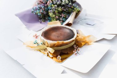 Çukulatalı, yanmış cheesecake ve masa başında çiçek.