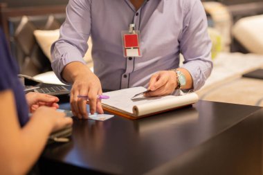 Tezgâhtaki kadın müşteriyle el ele tutuşan satıcı.