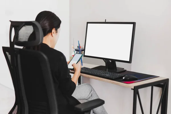 Mulher de negócios usando telefone inteligente enquanto trabalhava no computador no escritório em casa. — Fotografia de Stock