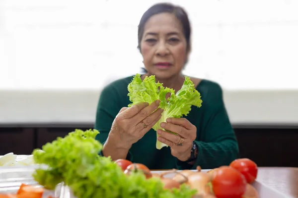 Mujer mayor preparar ensalada verde de lechuga y tomate. —  Fotos de Stock