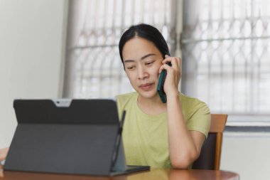 Hatlarda çalışan, cep telefonuyla konuşan ve dizüstü bilgisayarda gezinen güzel bir kadın..