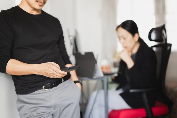 Businessman using mobile phone while woman working in background. — Stock Photo, Image