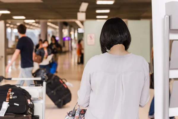 Frau quält sich am Flughafen mit Gepäck, das auf Abflug wartet. — Stockfoto