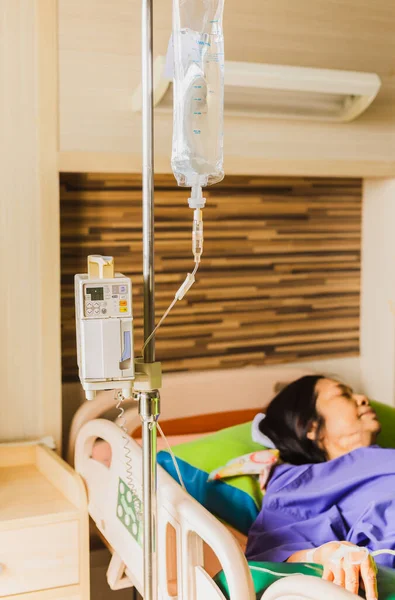 Mano de paciente mayor con solución salina inyectable acostada en la cama del hospital. — Foto de Stock