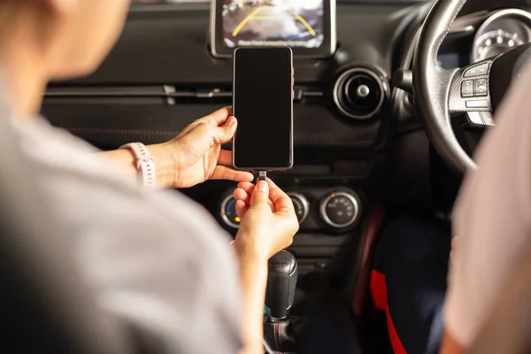 Vrouw opladen batterij smartphone in de auto. — Stockfoto
