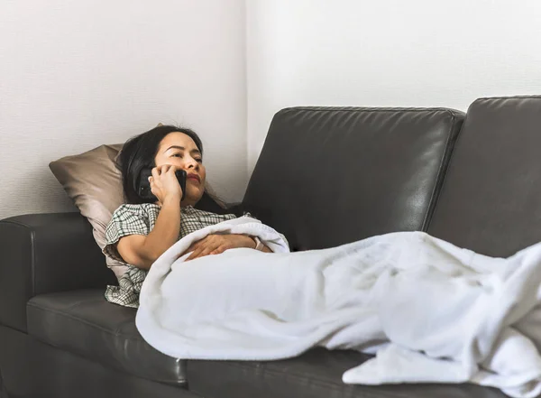 Kvinna som ligger på en soffa talar om smartphone karantän koncept. — Stockfoto