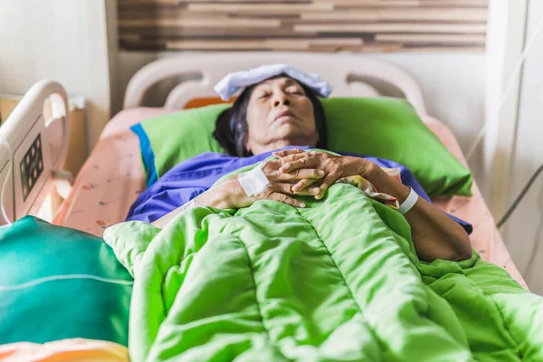 Mano de paciente mayor con solución salina inyectable acostada en la cama del hospital — Foto de Stock