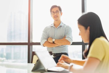 Sekreter dizüstü bilgisayarla çalışırken işadamı kolları bağlı vaziyette ofiste duruyor..
