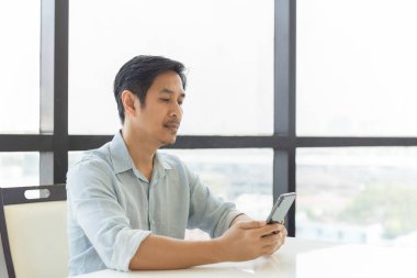 Yakışıklı adamın portresi evde akıllı telefon kullanarak rahatlıyor..