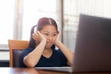 Genç kız evde dizüstü bilgisayara bakarak çalışmaktan yoruldu..