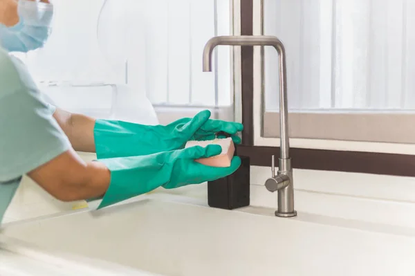 Mano femenina con guante sujetando esponja y presionando detergente líquido para lavar platos. — Foto de Stock