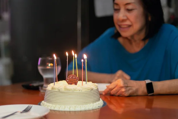 Töchter zünden Kerzen an Seniorin mit Geburtstagstorte an. — Stockfoto