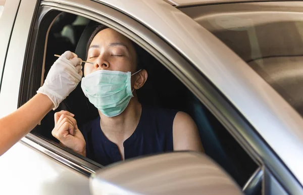 Medical worker taking nasal swab from woman in car to test for covid-19 infection. — Stock Photo, Image