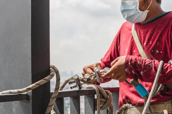 Bauarbeiter halten Stahlhaken in der Hand, die mit einem Seil für selbstabsorbierende Sicherheitseinrichtungen verbunden sind. — Stockfoto