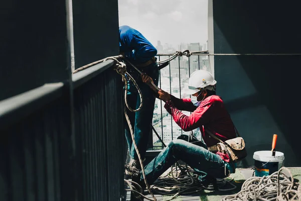 Two painter worker hands pulling the rope working on top of building. —  Fotos de Stock
