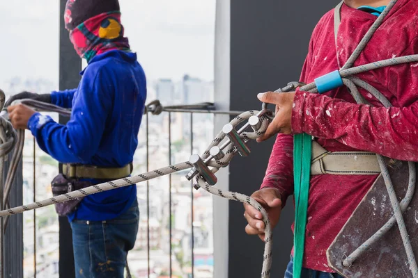 Trabalhador industrial ajustando equipamento de escalada preparando corda de segurança. — Fotografia de Stock