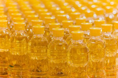 Arka planda plastik şişeler dolusu pişirme yağı.