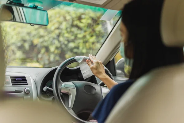 Mujer limpiando volante con toallita húmeda en un coche coronavirus pandemia. —  Fotos de Stock