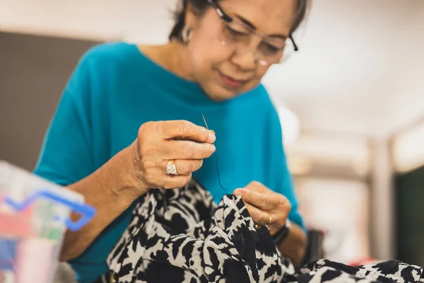 Idős nő kezek tűvel és cérnával, hogy megjavítsa a ruhát. — Stock Fotó