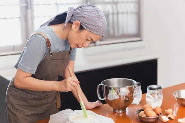 Woman beaker preparing cake mix dough in form for baking tin.