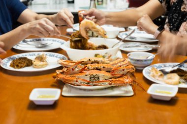 Asyalı bir aile evde taze mavi yengeçlerle yemek yiyor. İç mekan