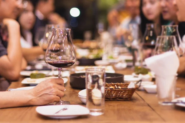 Grupo focal selecionado de amigos jantando no restaurante bebendo vinho tinto. interior — Fotografia de Stock