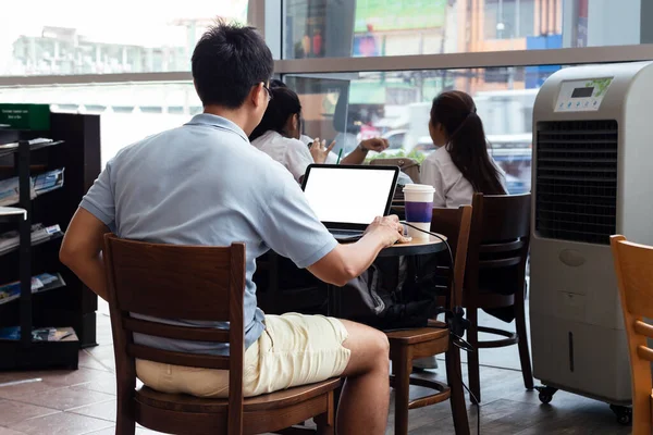 Asijský muž pomocí notebooku s prázdnou obrazovkou sedí u stolu v kavárně. vnitřní — Stock fotografie
