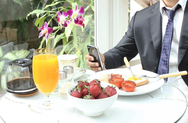 Affärsman med mobiltelefon under frukosten — Stockfoto