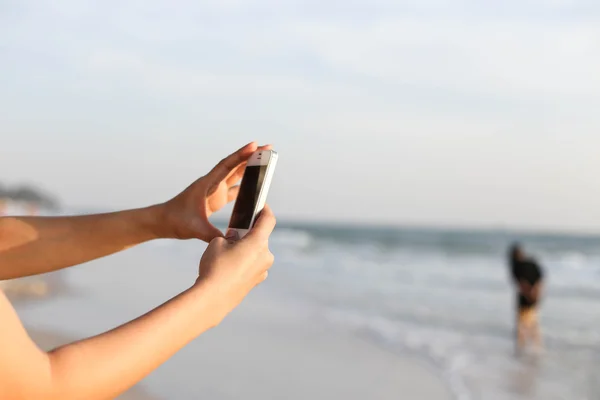 Kobiety z obraz przy plaży z inteligentny telefon — Zdjęcie stockowe