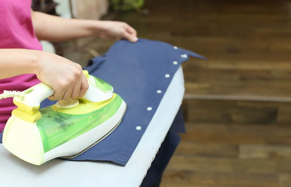 Mujer planchando una camisa azul — Foto de Stock