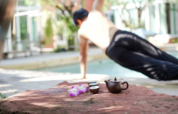 Homme faisant du Yoga et pot de thé — Photo