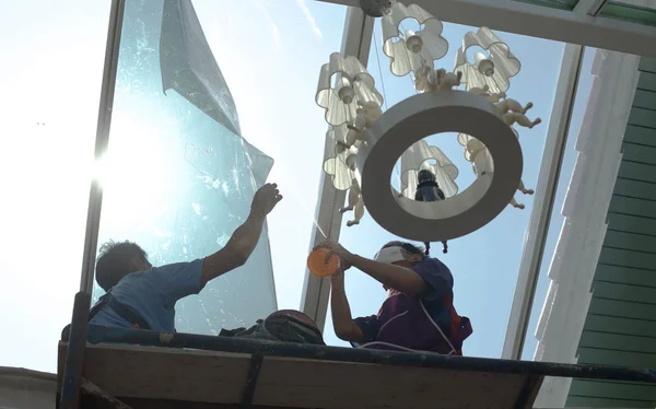Niet-geïdentificeerde mensen wrappers een glazen huis venster verven — Stockfoto