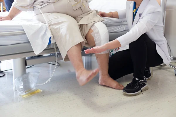 Doktor fizik tedavi hasta için bir diz yaralanması ile yapıyor.