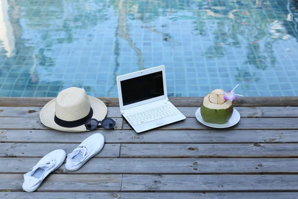 Ordinateur portable et boisson à la noix de coco près de la piscine — Photo
