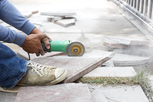 Amoladora trabajador corta una baldosa de piedra —  Fotos de Stock
