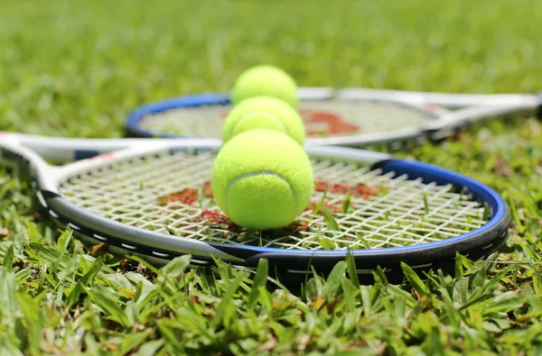 Tennis racket with balls on the grass