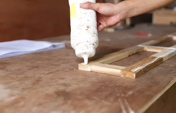 Carpintero poniendo pegamento en un pedazo de madera — Foto de Stock