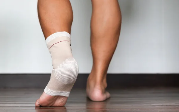 Tornozelo e pé lesionados envoltos em bandagem — Fotografia de Stock