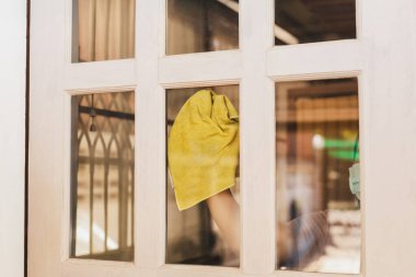 Hizmetçi, evde cam kapı temizliği yapıyor.