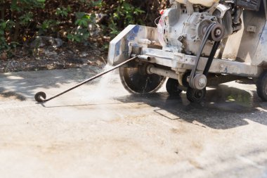 Beton bir testerenin kapağı su soğutma sistemiyle kaldırımı kesiyor.