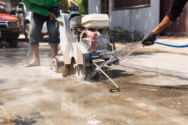 Yol işçisi yol onarımı sırasında benzinli testereyle beton kesiyor.