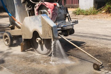 Beton bir testerenin kapağı su soğutma sistemiyle kaldırımı kesiyor.
