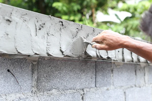 Asiatische junge Hand mit Kelle mit nasser Betonwand — Stockfoto