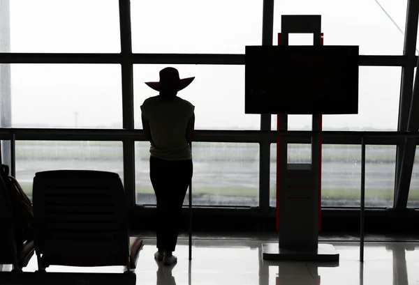 Woman standing near window in airport terminal — Stock Photo, Image