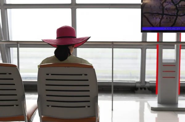 Woman with a pink hat waiting for a flight in the airport termin — Stock Photo, Image