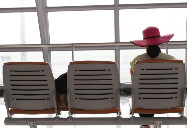 Woman with a pink hat waiting for a flight in the airport termin — Stock Photo, Image