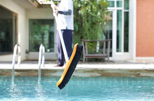Mna reinigt ein Schwimmbad mit einer Bürste — Stockfoto