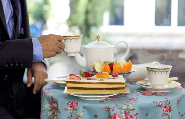 Affärsman med te med kakor och färsk frukt — Stockfoto