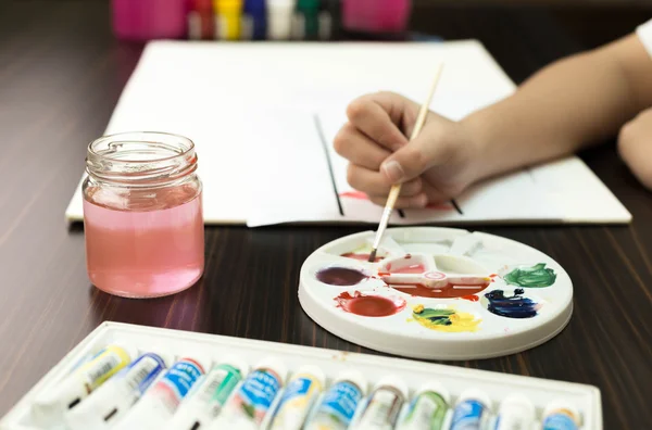 Niño mezcla pintura de diferentes colores en la paleta —  Fotos de Stock